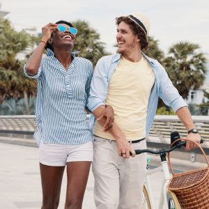 The Grove at Stone Park apartment homes with A smiling couple walks with a bicycle on a sunny day, enjoying each other's company outdoors.