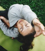 The Grove at Stone Park apartment homes with Woman practicing yoga outdoors on a green mat, stretching with eyes closed on a grassy surface.