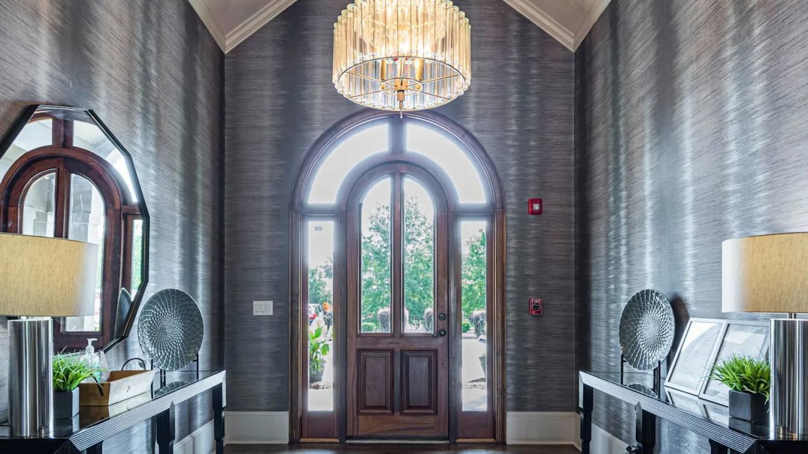 The Grove at Stone Park apartment homes with A grand entryway with double doors, a large chandelier, side tables, and a gray rug.