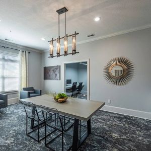 Modern meeting room with a rectangular table, four chairs, armchairs by the window, and decorative wall accents.