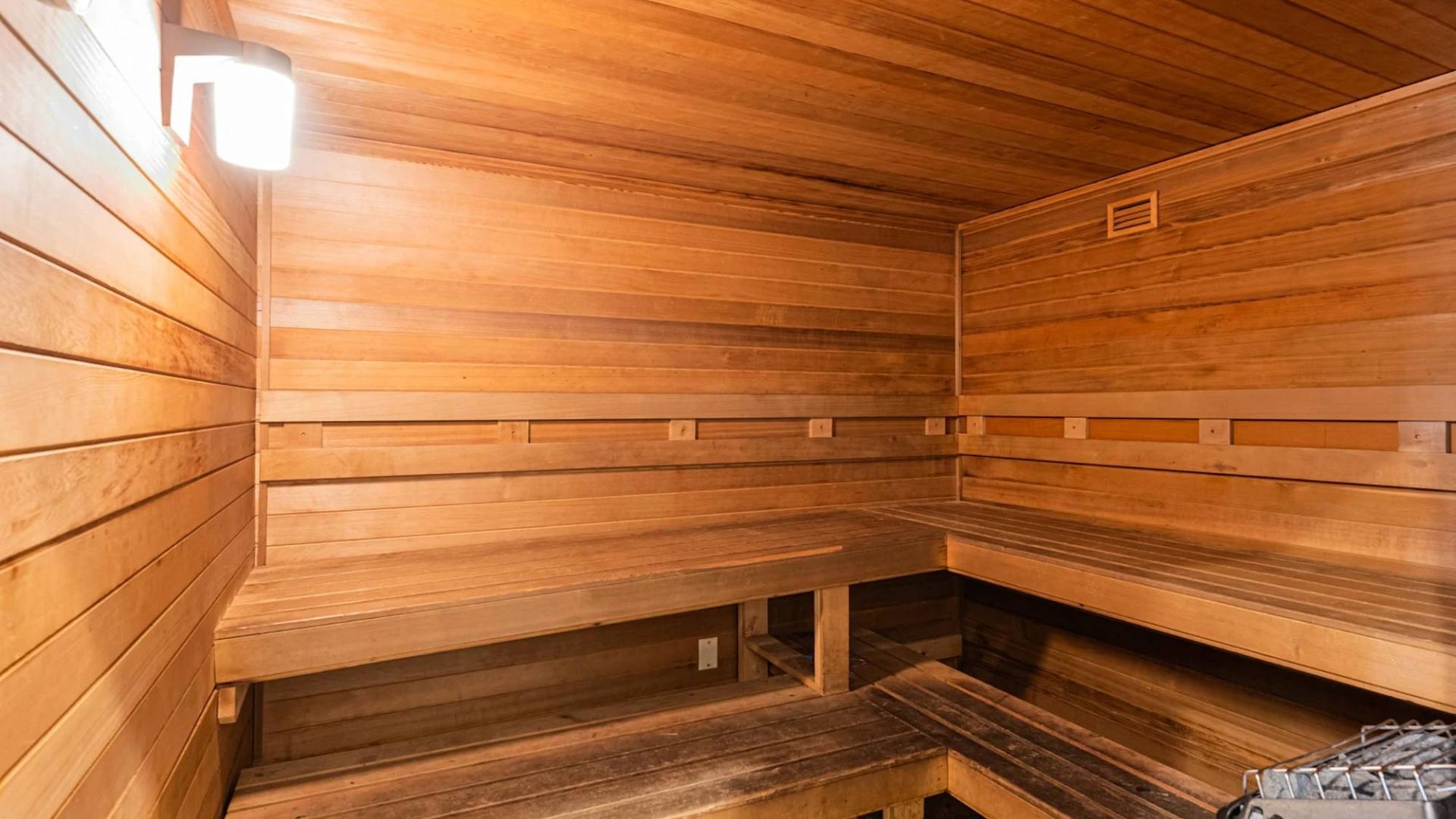 The Grove at Stone Park apartment homes with Wood-paneled sauna room with tiered benches and a heater in the corner under warm lighting.