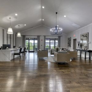 The Grove at Stone Park apartment homes with Modern lobby with wood floors, marble reception desk, seating area, large windows, and contemporary lighting fixtures.