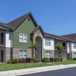 The Grove at Stone Park apartment homes with Modern two-story apartment buildings with gabled roofs and landscaped lawns under a clear blue sky.